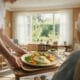 Un soignant apporte un plateau-repas équilibré à une personne âgée assise près d'une fenêtre, illustrant la prise en charge nutritionnelle de la dénutrition